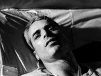 John McCain liggend op een bed in Hanoi Hilton