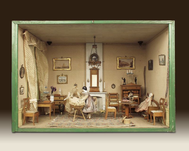 Biedermeier woonkamer met wieg, gemaakt rond 1835 – foto door J & M Zweerts, Den Haag (Collectie Haags Historisch Museum) - Lita heeft deze woonkamer zelf ingericht in de Biedermeierstijl. Deze stijl was erg populair onder de gegoede burgerij in de periode 1815-1850. De meubels, gordijnen, wandbespanningen en kleding zijn redelijk sober van vorm en kleur. Dit in tegenstelling tot de Empirestijl, die eerder huiskamers vulde met verguldsel en andere kostbare materialen. In de hoek heeft Lita een wieg geplaatst. Hierin ligt een baby, gekleed in een katoenen hemdje. Op de commode staat het bordspel triktrak en op de klep van de schrijftafel staat een ivoren inktstel. Aan de muren hangen 19de-eeuwse kunstwerkjes en in de rechterhoek hangen twee zogenaamde schellenkoorden. Daarmee kon de dame of heer des huizes de dienstmeid roepen. De koorden lopen namelijk door tot in de keuken. Daar hing aan het einde van het koord een belletje. 