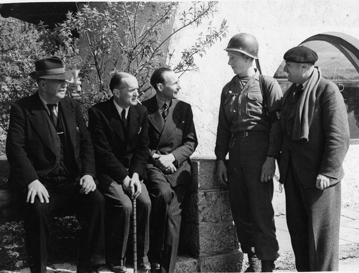 Iemand van de militaire politie van het Zevende Leger praat na hun bevrijding met (van links naar rechts), Léon Jouhaux, François de La Rocque, Jean Borotra en Marcel Granger.
