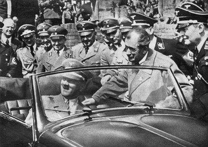 Adolf Hitler in een Volkswagen Kever cabriolet na de eerste steenlegging van de fabriek in 1938 met Jakob Werlin (rechts) en Ferdinand Porsche (tweede van rechts).