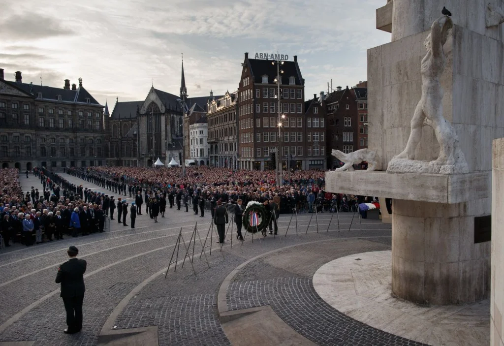 De Koning en Koningin leggen de eerste krans vlak voor de twee minuten stilte bij het Nationaal Monument op de Dam in Amsterdam.