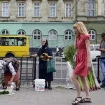 Een paradox tussen oud en jong - oudere vrouwen verkopen zelfgekweekte groente op straat. Jongeren zijn druk met hun mobieltje. (Lviv, stad van paradoxen)