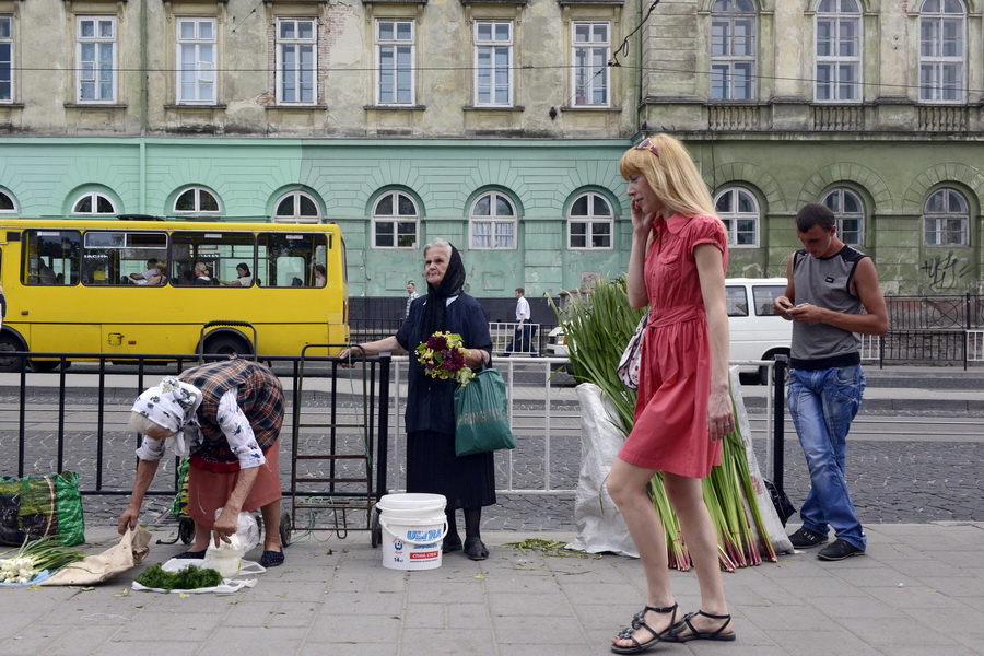 Een paradox tussen oud en jong - oudere vrouwen verkopen zelfgekweekte groente op straat. Jongeren zijn druk met hun mobieltje. (Lviv, stad van paradoxen)