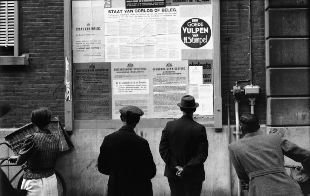 Dordtenaren bekijken de aankondigingen van de staat van oorlog en beleg, de voormobilisatie, de algemene mobilisatie van 28 augustus 1939 en de vordering van motorrijtuigen op het aanplakbord bij het Stadhuis. Foto W. Meijers
