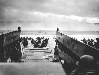 Beroemde foto van D-Day. Amerikaanse soldaten van de USS Samuel Chase verlaten de landingsboot op Omaha Beach op 6 juni 1944