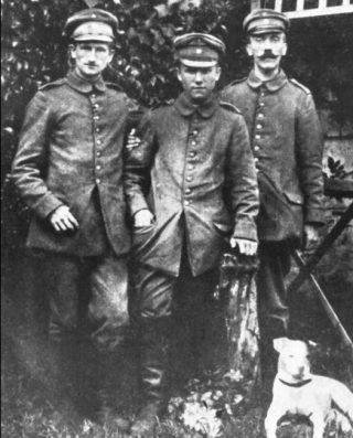 Deze in april 1915 in Fournès genomen foto is voor zover bekend de eerste foto van de regimentskoeriers Ernst Schmidt, Anton Bachmann en Adolf Hitler. Aan Hitlers voeten de foxterriër Foxl, die op een dag aan is komen lopen en sindsdien Hitlers favoriete metgezel is. 