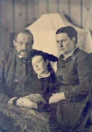 Foto uit de Victoriaanse tijd van een echtpaar dat zich laat fotograferen met hun overleden dochter