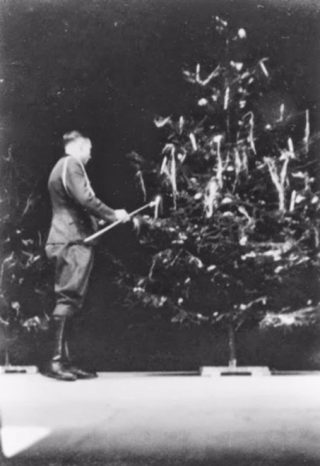 SS-officier Karl Hoecker steekt in Auschwitz kaarsjes aan in de kerstboom, slechts drie weken voor de bevrijding van het kamp. (USHMM)