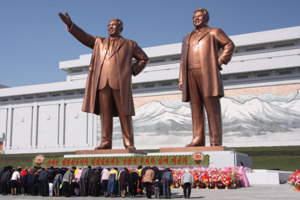 Noord-Koreanen buigen voor de standbeelden van Kim Hong-Un's vader en grootvader - cc