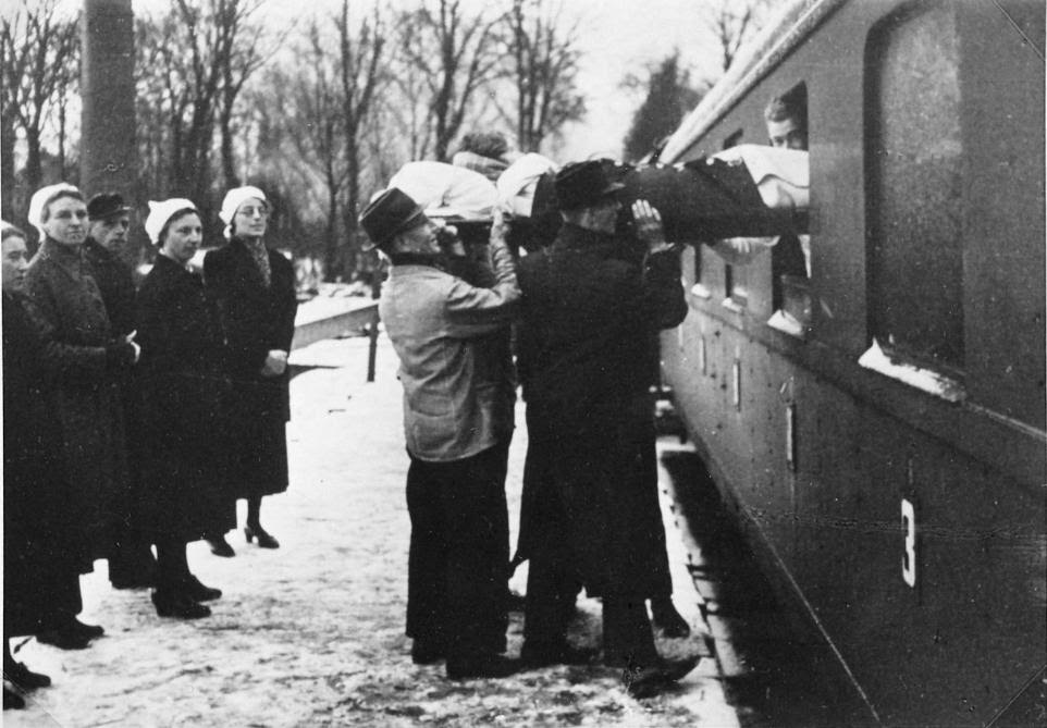 Een bedlegerige evacuée uit een ziekenhuis bij Santpoort wordt met op een brancard in de trein getild.