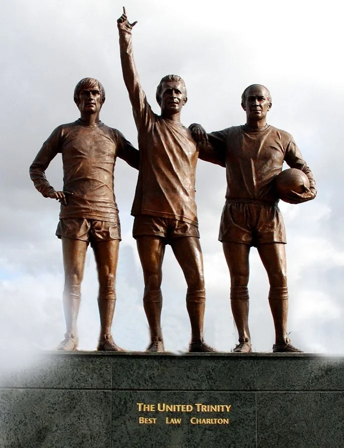 Beelden bij Old Trafford van drie belangrijke spelers uit de geschiedenis van Manchester United: George Best, Denis Law en Bobby Charlton - cc