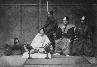 Foto uit 1897 van een in scène gezette Seppukuceremonie. De man in het wit pleegt harakiri / seppuku. (Publiek Domein - wiki)