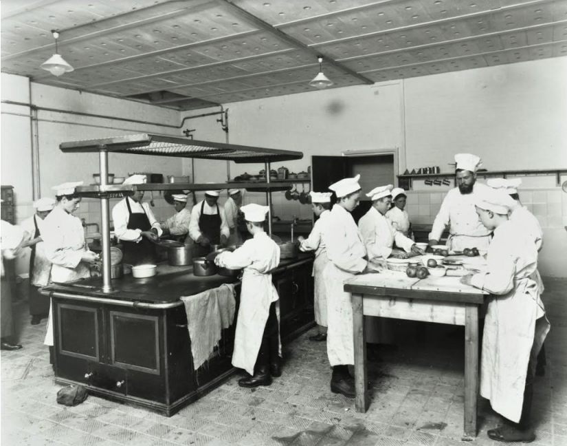 Een jonge Iwan Kriens houdt toezicht in de keuken tijdens een kookles (1914). Foto Collectie London Metropolitan Archives.