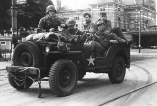 Duitse soldaten in een buitgemaakte Amerikaanse jeep in Arnhem. Jonge SS officieren hebben deze buitgemaakt, achterin zitten twee krijgsgevangen Britse parachutisten. (Bron: Oorlogsbronnen, collectie NIOD)