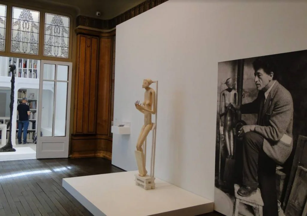 Werk van Giacometti met daarnaast een foto van de kunstenaar uit 1954 
