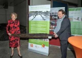 Gedeputeerde Willy de Zoete (Provincie Zuid-Holland) overhandigt een van de Romeinse palen aan RMO-directeur Wim Weijland. (Foto: RMO)