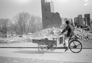 Een man rijdt met een bakfiets langs de ruïne van de vrijwel gesloopte R.K. kerk in Den Haag, op de hoek van de eveneens bijna gesloopte Stadhouderslaan wegens aanleg van de 'Atlantikwall'. - Menno Huizinga