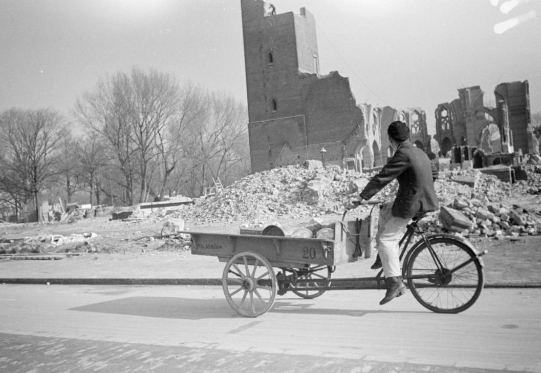 Een man rijdt met een bakfiets langs de ruïne van de vrijwel gesloopte R.K. kerk in Den Haag, op de hoek van de eveneens bijna gesloopte Stadhouderslaan wegens aanleg van de 'Atlantikwall'. - Menno Huizinga