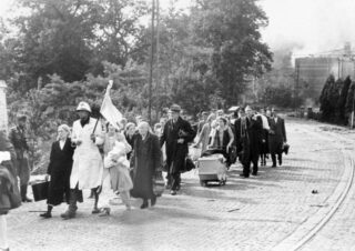 Evacués uit het Elisabethgasthuis onderweg, begeleid door een verpleegster met een witte vlag.