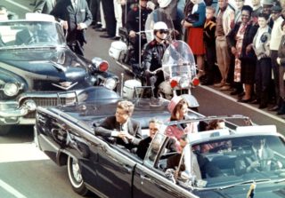 John F. Kennedy (links) en zijn vrouw in de limousine, kort voor de aanslag