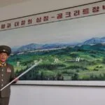 Een Noord-Koreaanse official wijst op een landkaart de scheiding tussen Noord- en Zuid-Korea aan