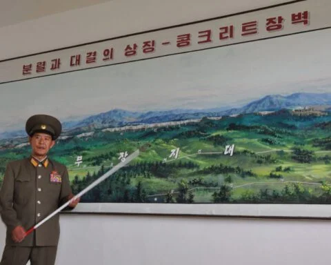 Een Noord-Koreaanse official wijst op een landkaart de scheiding tussen Noord- en Zuid-Korea aan