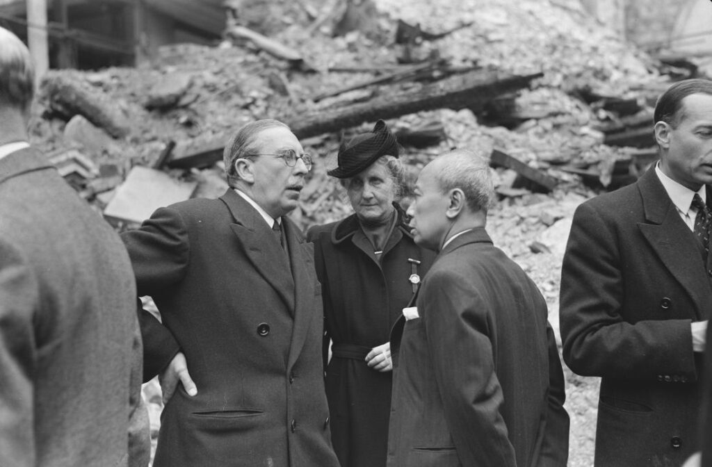 Soejono (rechts) spreekt met de Nederlandse ambassadeur in Londen, Michiels van Verduynen, en diens vrouw bij de ruïne van de Nederlandse kerk in Austin Friars. Het is 10 mei 1942, een maand voor Soejono’s aantreden als minister.