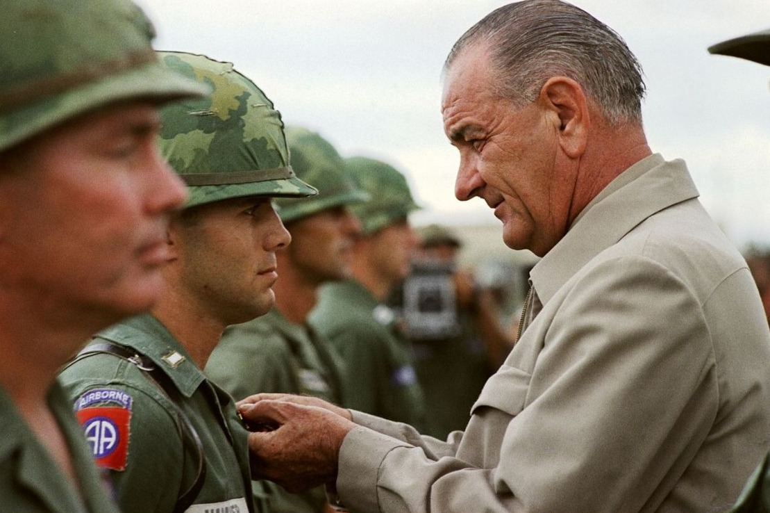 President Johnson reikt een onderscheiding uit aan een Amerikaanse militair tijdens een bezoek aan Vietnam, oktober 1966