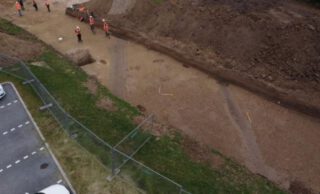 Beeld vanuit de lucht. Bermgreppels van de Romeinse weg, zichtbaar als donkere, rechte banen.