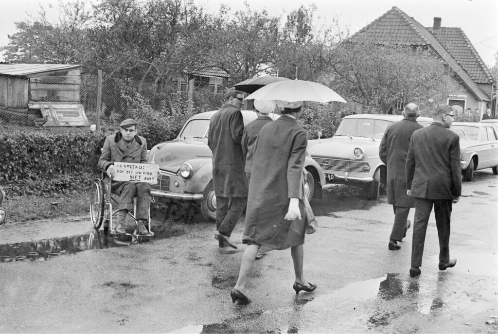 Kerkgangers worden geconfronteerd met demonstrant die oproept kinderen in te enten tegen polio, Elspeet 1966, ANP