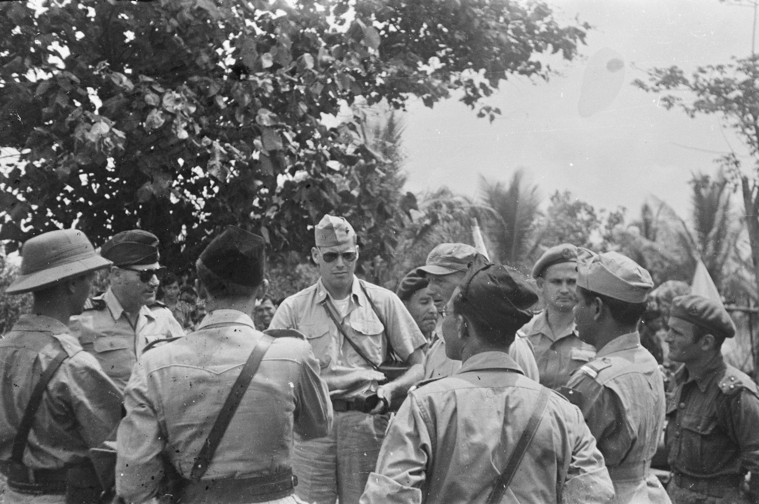 Nederlandse en Indonesische officieren overleggen in januari 1948 op Sumatra met internationale militaire waarnemers. In het midden met zonnebril de Amerikaanse kapitein J.A. Mac Naill, links naast hem, ook met zonnebril de Franse kapitein J. Rousset.