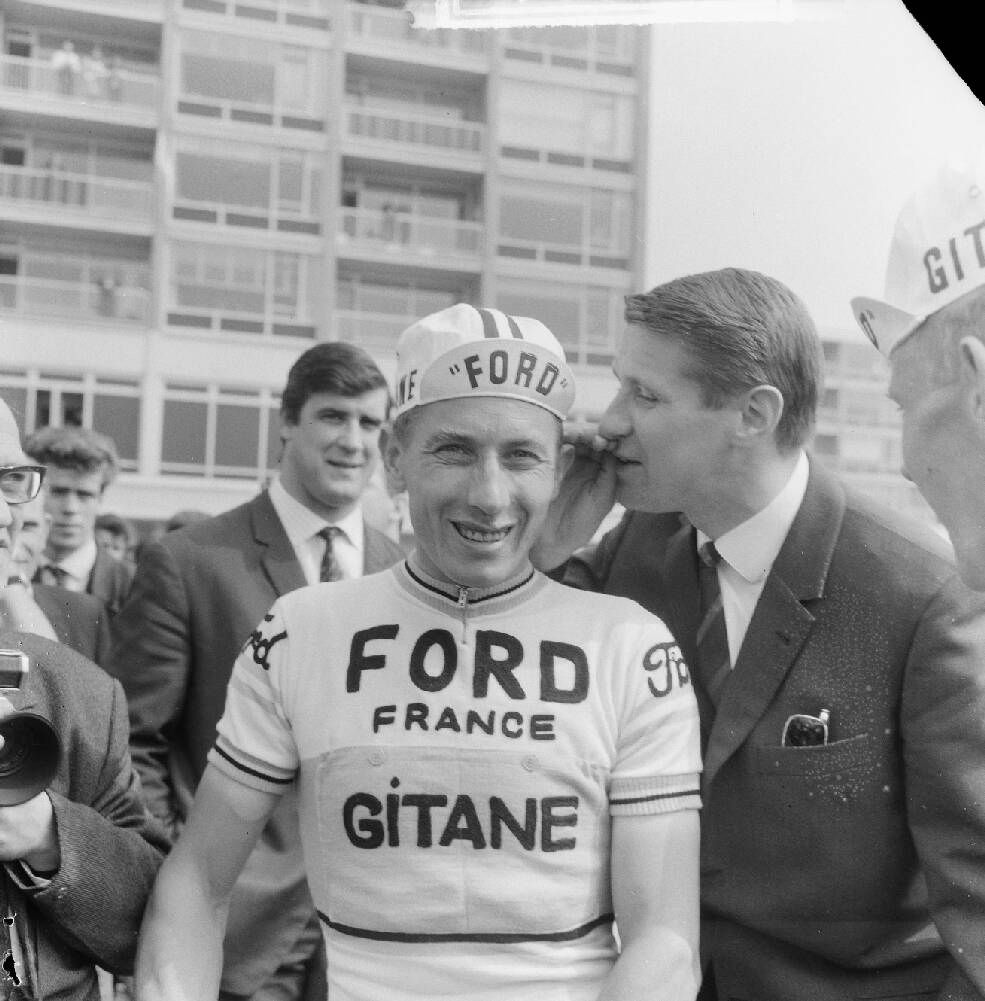 Anquetil in Amstelveen bij de start van de Ronde van Nederland 1965. Peter Post fluistert hem iets in, op de achtergrond Anton Geesink.