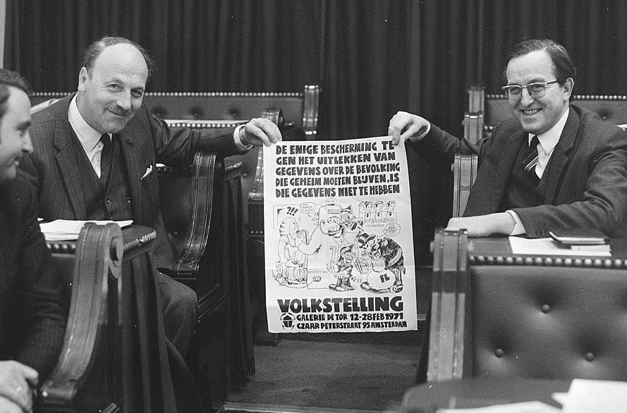 Tijdens een debat in de Tweede Kamer over de volkstelling tonen  tegenstanders Schakel (AR) en Aarden (PPR) een affiche tegen de stelling, februari 1971