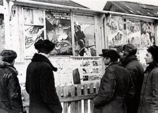 Ergens in de bezette Sovjet-Unie bekijken burgers een uithangbord met anticommunistische propagandaposters (maker en herkomst onbekend).
