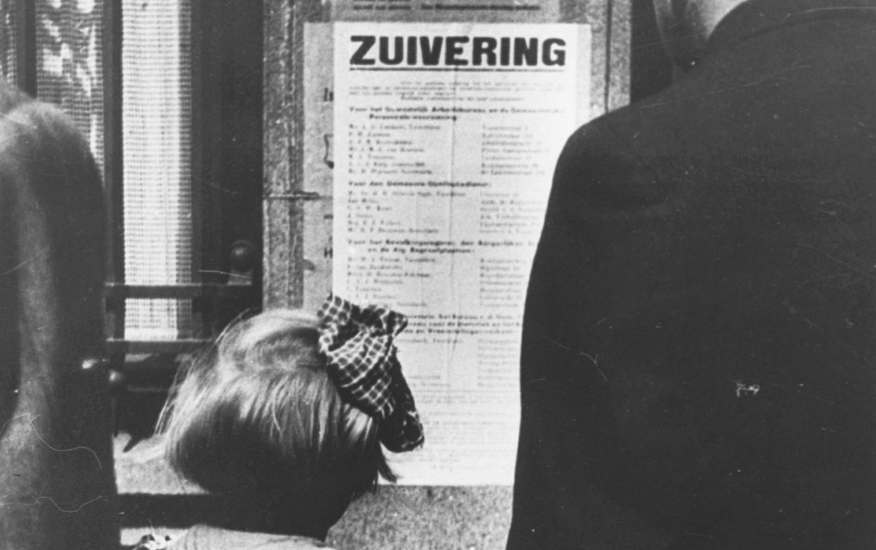 Een meisje kijkt naar een affiche over zuivering, na mei 1945. Collectie NIOD.