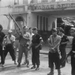 Indonesische strijders op 12 november 1949 voor de uitgebrande Pasar Gede ofwel Grote Markt(hal) in Solo, Midden-Java.