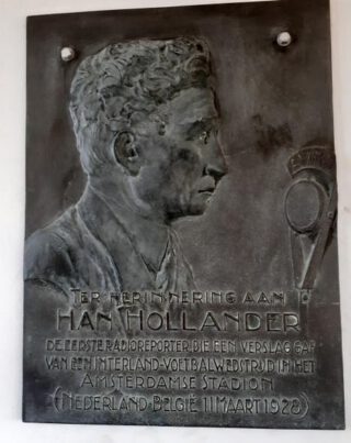In de oude radiokamer onder het dak van de marathontribune van het Olympisch Stadion hangt een plaquette die herinnert aan de legendarische radio-pionier Han Hollander. 
