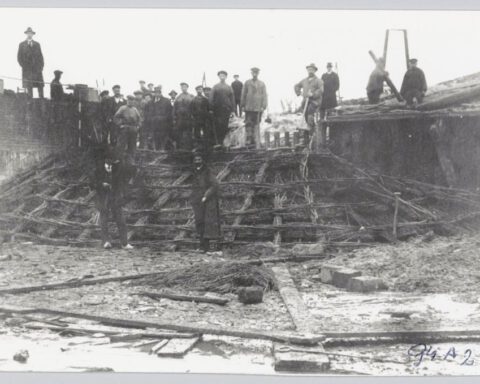 Grote groep mannen bij een zinkstuk voor onderhoud aan een strekdam - Historische Vereniging Callantsoog