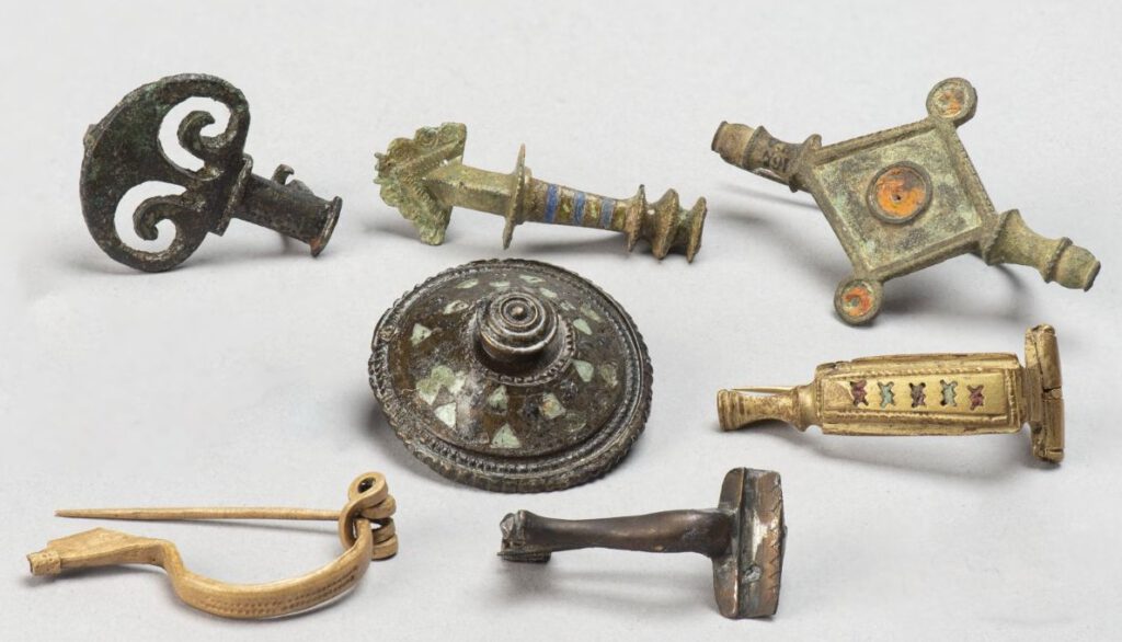 Mantelspelden van brons. Sommigen zijn ingelegd met email. Lengte mantelspeld rechtsboven 5,6 cm., 100-300 na Chr., uit Vechten