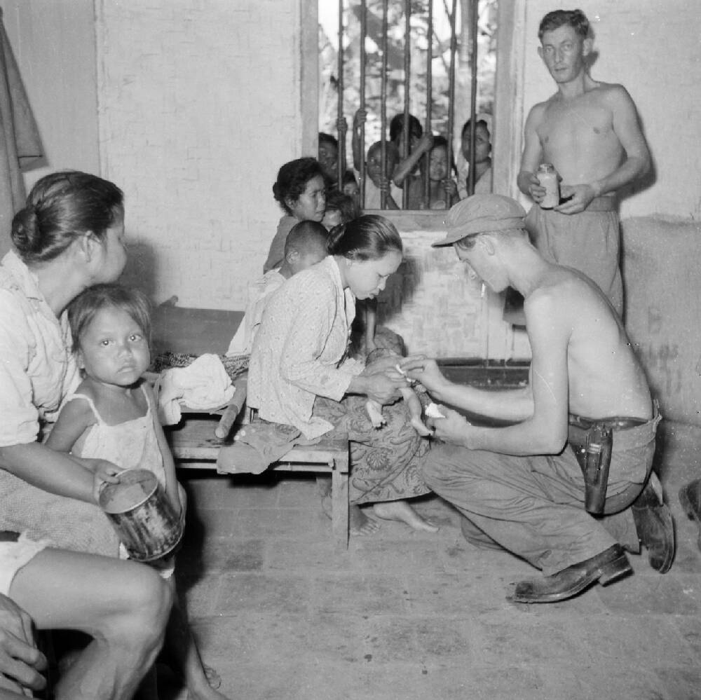 Nederlandse militairen bekommerden zich ook om de plaatselijke bevolking. Hier behandelt een militair in 1946 een zieke baby op Java, plaats onbekend.