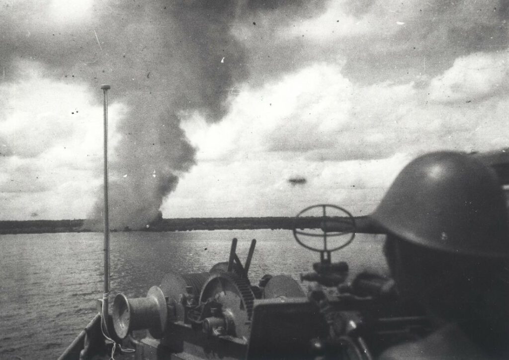 Patrouilleboot RP-133 vuurt met het 3,7 cm-kanon op de kust. Vermoedelijk gaat het om de beschieting van het dorp Sungai Bela op de oostkust van Sumatra op 17 november 1947. Er ontstond daardoor brand in de haven en een aantal huizen werd beschadigd. 