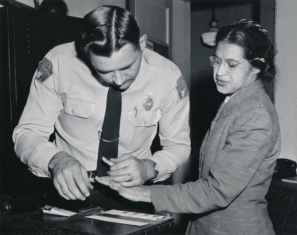 Een agent neemt vingerafdrukken af bij Rosa Parks, nadat haar arrestatie omdat ze haar plaats in de bus niet heeft afgestaan aan een blanke.