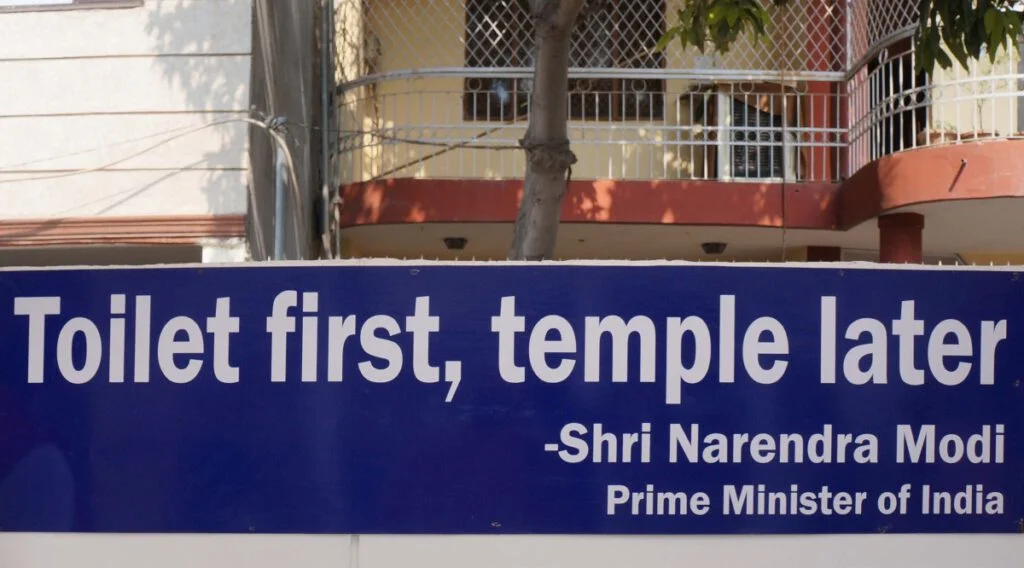 De slogan van minister-president Modi op een bord aan de rand van de Sulabh campus.
