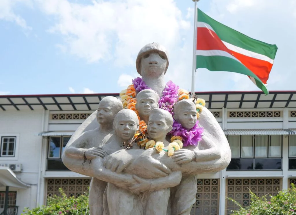 Voor het Kabinet van de Surinaamse president drukt ‘Mama Sranan’ al haar kinderen koesterend tegen zich aan.