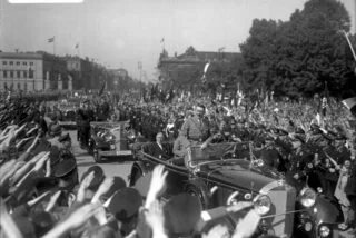 Adolf Hitler tijdens een rondrit door Berlijn op 1 mei 11933. Zittend in de auto Franz von Papen