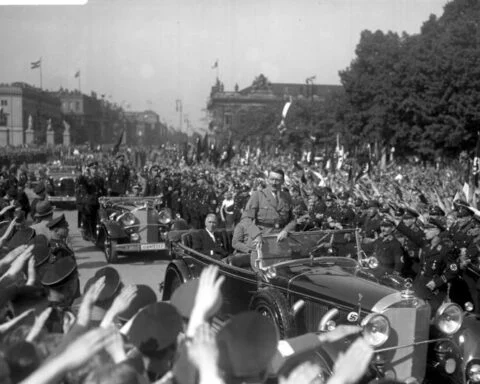 Adolf Hitler tijdens een rondrit door Berlijn op 1 mei 11933. Zittend in de auto Franz von Papen