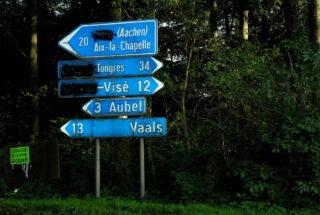 De taalgrens leidt soms ook tot een taalstrijd. Hier in Voeren zijn de plaatsaanduidingen in de niet gewenste taal (in dit geval het Nederlands) onleesbaar gemaakt.