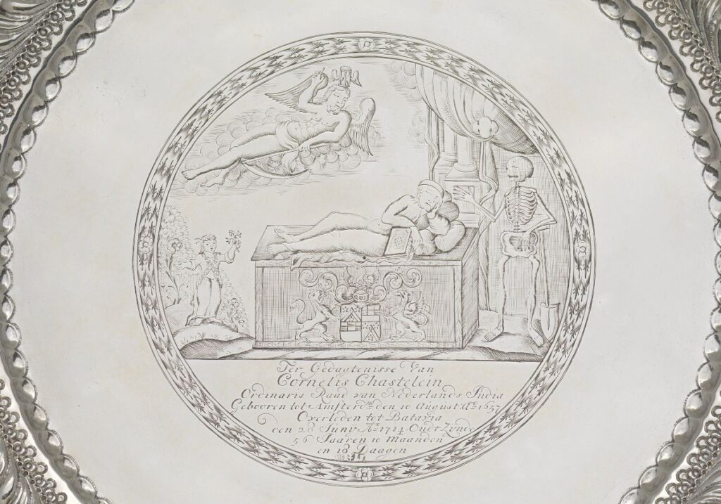 Ter gelegenheid van het overlijden van Cornelis Chastelein liet zijn familie dit zilveren dienblad maken, Te zien zijn de overledene met een boek op de kist, rechts de dood, verder een engel op een wolk en links een meisje met een bloem in haar hand. 