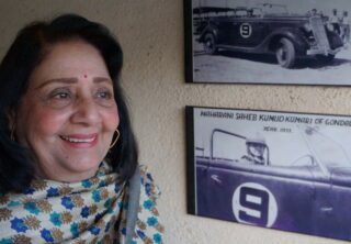 De maharani poseert bij een foto van haar racewagen.