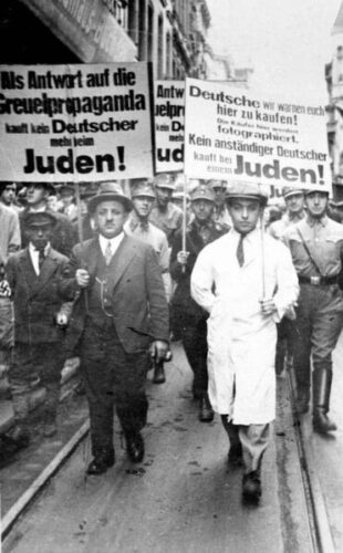 Joden worden tijdens de anti-Joodse boycot van 1 april 1933 gedwongen rond te lopen met borden met een antisemitische boodschap.